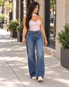 FV26 Jean Omg con blusa rosa: Jessica caminando por la calle, mirando hacia un lado.
